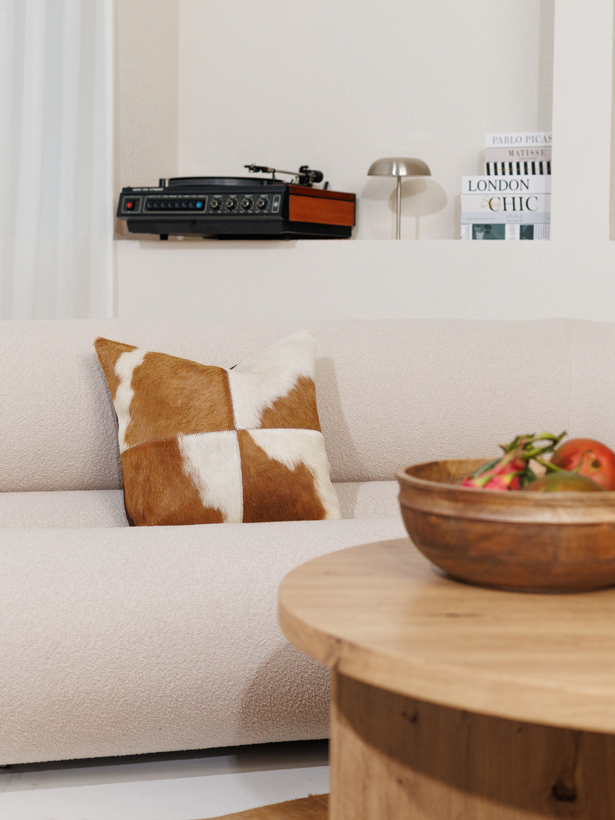 Kuhfell-Kissenbezug in Braun-Weiss auf einem hellen Sofa