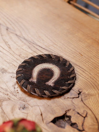 Kuhfell-Untersetzer mit Hufeisen auf einem Holztisch, aus der Nähe